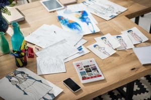 smartphone, digital tablet with pinterest website and fashion sketches on table