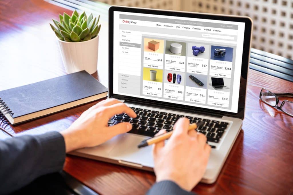 Online shop website developer working with a laptop, office desk background.